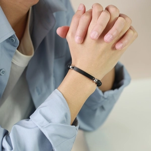 Herrenarmband aus matten schwarzen Onyxperlen mit Metallplatte am Handgelenk getragen