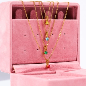 Detail of four gold birthstone necklaces with colorful zircon pendants in a pink velvet box