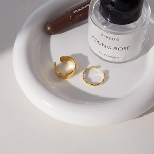Detail of 18k gold plated stainless steel hammered rings set on a white ceramic tray