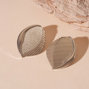 Detail of silver leaf earrings with precision metallic stripes and polished edges