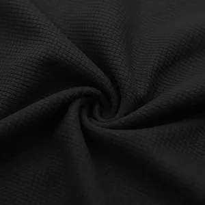 Close-up of black waffle knit fabric texture showing breathable 3D structure on summer set
