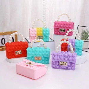 Various colorful silicone pop-it purses for kids with pearl handles and gold clasps