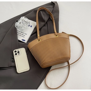 Brown PU leather tote bag with vertical pleated texture and metal ring on grey suit