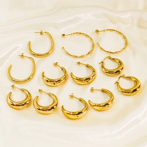 Golden C-shaped stainless steel earrings set with crystal rhinestones on silk background
