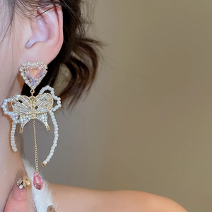 Detail view of butterfly pearl tassel earrings with sparkling crystals and golden finish