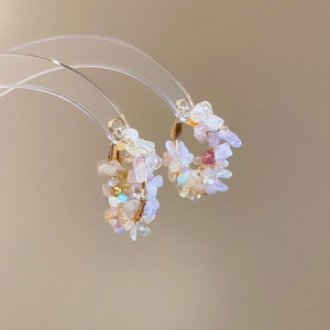 Close-up of gold hoop earrings with multi-color pastel stones and natural textures
