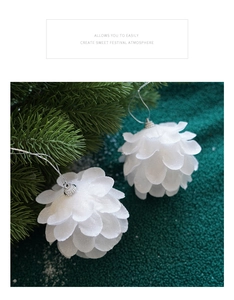Close-up of white petal-shaped glitter Christmas balls hanging on pine branches