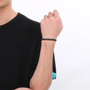 Détail du bracelet gourmette noir mat avec fermoir OT crâne sur le poignet d'un homme