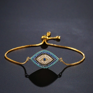 Detail of gold evil eye bracelet with blue and white zircons on a dark surface
