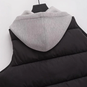 Schicke schwarze Steppweste mit grauer Strickkapuze und minimalistischem Patchwork