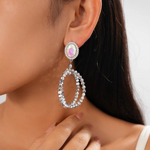 Macro view of geometric oval earrings with colorful crystals and silver beaded double hoops