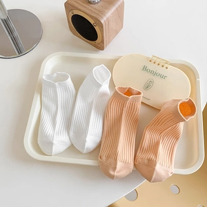 Pair of ribbed cotton ankle socks in white and orange with minimalist home decor