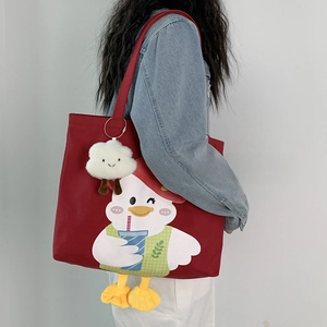 Detail of red canvas tote bag with cartoon duck print and fluffy cloud pendant charm