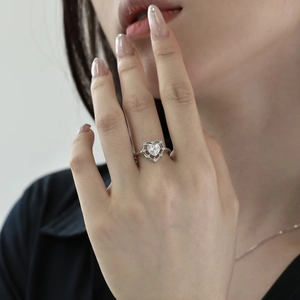 Close-up of heart-shaped pink zircon ring with halo crystals on female finger