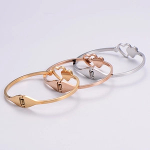 Detailed close-up of heart-shaped open bangles in gold, rose gold and silver finishes