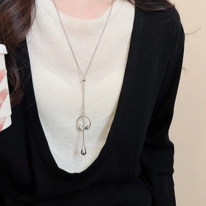 Detailed close-up of a tiger eye pearl silver sweater chain on a model sweater