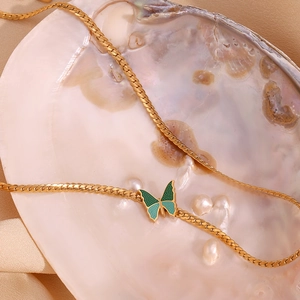 Detail of 18K gold butterfly necklace with teal enamel on NK chain in shell