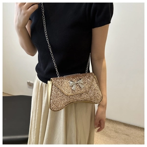 Detail view of the elegant golden evening bag featuring a sparkling silver bow decoration
