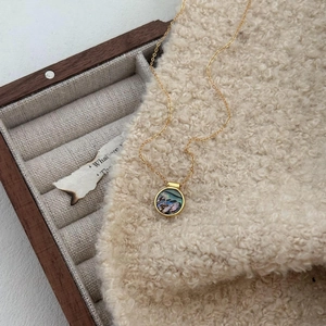 Macro detail of 925 silver gold-plated necklace with iridescent abalone shell pendant
