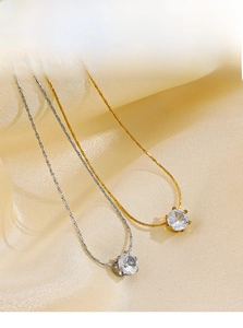 Detailed view of gold and silver six-prong cubic zirconia necklaces on satin fabric