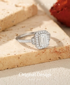 Macro detail of emerald cut moissanite ring with halo setting on stone surface