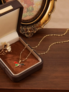 Close-up of a 18k gold-plated dragonfly necklace with colorful inlay in a vintage box
