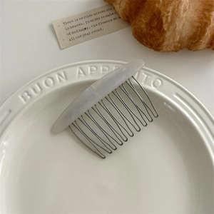 Detail of marble pattern acetate hair comb on ceramic plate with aesthetic ins style