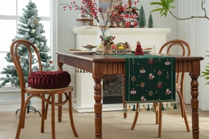 Detailed knit Christmas table runner with festive Santa and gift patterns and soft tassels