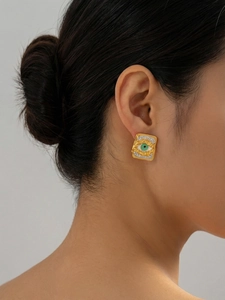 Close-up of square gold-plated evil eye stud earrings with white zircon on ear model