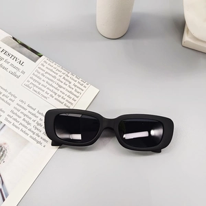 Detailed close-up of matte black rectangular sunglasses for kids on a minimalist grey surface