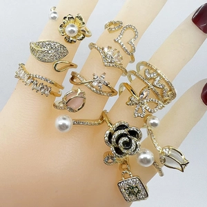 Close-up of assorted gold rings featuring flower, butterfly, and pearl accents on hand