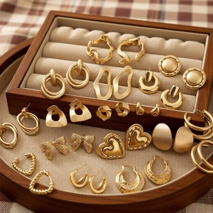 Detail view of gold earring set with heart and bow designs in a luxury jewelry box