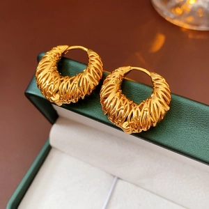 Detail of 18k gold plated hoop earrings with woven texture in a dark green jewelry box