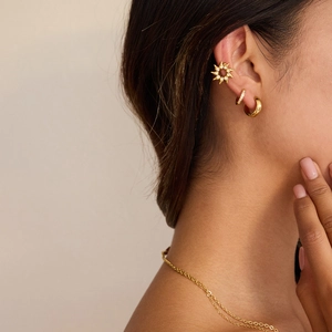 Gros plan sur la boucle d'oreille soleil avec strass et boucles en acier doré 18 carats