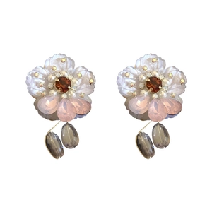 Elegant floral stud earrings with orange crystals and teardrop pearls on white background