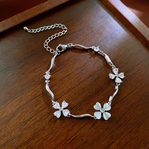 Silver bracelet featuring zircon clover charms on a luxury dark wood textured background