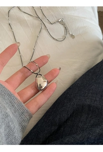 Close-up of minimalist silver liquid metal teardrop pendant with double layer chain