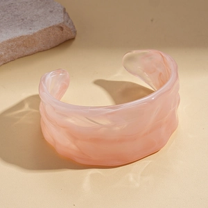 Detail of pink acrylic open cuff bracelet featuring marble texture and wavy pattern