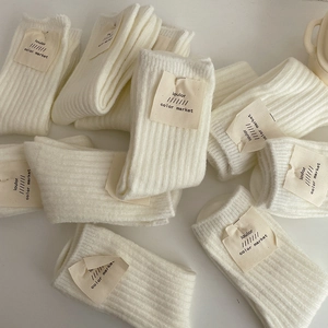 Close-up of thick beige wool socks showing knit texture and premium brand tags