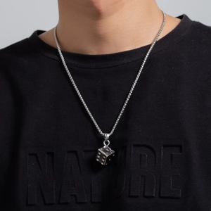 Detail view of a silver stainless steel dice pendant worn on a black casual shirt
