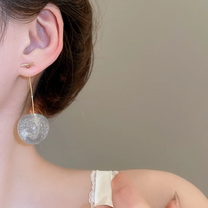 Gros plan de boucles d'oreilles pendantes sphériques grises et dorées sur un modèle