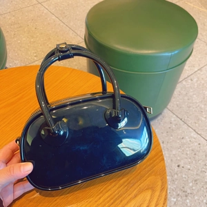 Glossy black PVC mini jelly handbag with top handles shown in a hand-held lifestyle setting