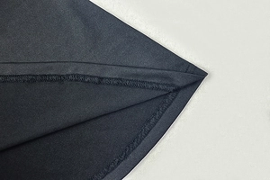 Gros plan sur les doubles coutures de l'ourlet d'une robe moulante sombre