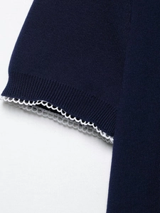 Gros plan détaillé sur la manche en tricot bleu marine et sa bordure en dentelle blanche