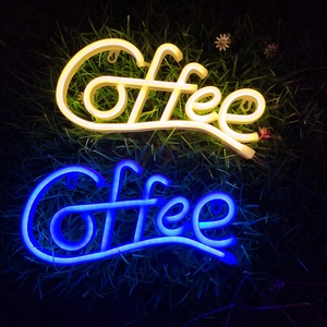 Close-up of blue and warm yellow LED Coffee neon signs displayed on green grass