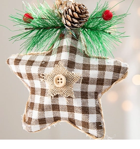Detail of burlap star ornament with pine cones, needles and red berries on plaid fabric