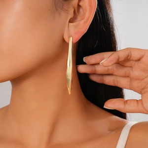 Gros plan de boucles d'oreilles minimalistes longues et courbées en or 18 carats