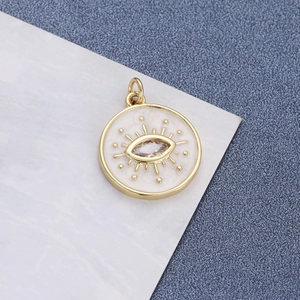 Detail of a gold-plated evil eye pendant with white enamel and clear cubic zirconia crystal