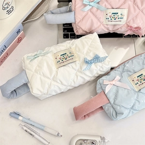 Flat lay of macaron-colored quilted cosmetic bags with bows and handles on a desk