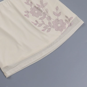 Gros plan du motif floral en strass sur tissu mesh beige pour ensemble automne